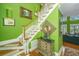 Elegant staircase with white balusters and wooden handrail, accented by artwork and decorative lighting against green walls at 944 Hammocks Way, Edisto Island, SC 29438
