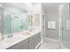 Luxurious bathroom featuring a double sink vanity, framed mirrors, white shiplap accent wall, and glass enclosed shower at 138 Maritime Way, Summerville, SC 29485