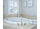 Soaking tub with travertine surround, a window with plantation shutters, and neutral decor for a calming bath experience at 1427 Shell Fish Ct, Mount Pleasant, SC 29466