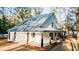 Side view of a modern home with metal roof, a covered porch, and natural light filtering through surrounding trees at 143 Harvest Way, Walterboro, SC 29488