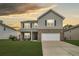 Charming two-story home with a manicured lawn, brick accents, and a two-car garage beneath a golden sky at 233 Old Carolina Dr, Goose Creek, SC 29445