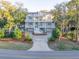 A beautiful three-story home with a white staircases, garage, and a private drive surrounded by a yard at 3204 Waterway Blvd, Isle of Palms, SC 29451