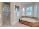 Bright bathroom features a glass-enclosed shower, soaking tub, and multiple windows, offering a spa-like experience at 4009 Ballovista Rd, Johns Island, SC 29455