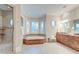 Spacious bathroom featuring tiled floors, a soaking tub, glass shower, double vanity, and lots of natural light at 4009 Ballovista Rd, Johns Island, SC 29455