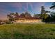 Stunning home exterior with a large lawn and well-lit façade at dusk, framed by mature trees at 4009 Ballovista Rd, Johns Island, SC 29455