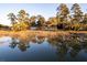 Scenic home exterior with a serene water view and trees reflecting in the foreground at 4009 Ballovista Rd, Johns Island, SC 29455