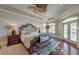 Main bedroom featuring a tray ceiling, ceiling fan, hardwood floors, and a bench at the foot of a luxurious bed with wooden accents at 4009 Ballovista Rd, Johns Island, SC 29455