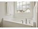 Bright white bathroom with soaking tub, chrome fixtures, and large window at 707 Alma Square Dr, Moncks Corner, SC 29461