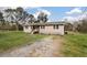 A ranch-style home with a gravel driveway and a cozy porch featuring the American flag at 8476 Old Georgetown Rd, McClellanville, SC 29458