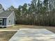 Expansive front yard featuring a long driveway, a home with dark siding, and a lush tree line in the background at 85 Prestwick Pl, Walterboro, SC 29488