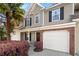 Two-story townhome featuring a single-car garage, black shutters and a blooming azalea bush at 8741 Grassy Oak Trl, North Charleston, SC 29420