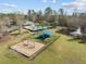 Aerial view of a playground, pool, pond with fountain, and tennis courts surrounded by trees at 9394 Harroway Rd, Summerville, SC 29485