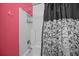 A well-lit white tiled bathtub and shower combination, accented by a bright pink wall and a patterned shower curtain at 9394 Harroway Rd, Summerville, SC 29485