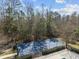 Aerial view of a blue tennis court surrounded by trees, bushes, and a black fence at 9394 Harroway Rd, Summerville, SC 29485