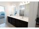 Modern bathroom featuring double sinks, dark cabinets, and mirrors, with a view to the shower at 112 Edisto Crossing Ct, Ridgeville, SC 29472