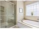 Bright bathroom with glass enclosed shower, tub, and window bringing the outdoors in to create a spa-like retreat at 1420 Polly Point Rd, Wadmalaw Island, SC 29487