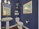 Powder room featuring blue walls, a pedestal sink, hardwood floors, and a decorative mirror and artwork at 1644 Fishbone Dr, Johns Island, SC 29455