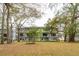 A modern condo building with multiple balconies overlooking a sprawling green lawn and mature trees at 1818 Orangeburg St, North Charleston, SC 29405