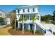 Charming two-story beach house with white siding, lovely shutters, and lush landscaping featuring palm trees at 4176 Victory Pointe Dr, Mount Pleasant, SC 29466