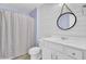 A farmhouse bathroom has a white vanity and a round mirror hanging above it, and a shower with a neutral curtain at 422 Sanders Farm Ln, Charleston, SC 29492