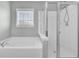 Bathroom featuring a white soaking tub next to a glass enclosed shower and window at 422 Sanders Farm Ln, Charleston, SC 29492