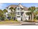 Charming coastal home featuring double garages, palm trees, and a welcoming staircase to the front door at 65 Ocean Point Dr, Isle of Palms, SC 29451