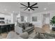 Open living space with hardwood floors, gray furniture, ceiling fan, and seamless flow into the kitchen at 87 Morning Song St, Summerville, SC 29485