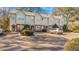 Exterior view of multi-unit townhomes, featuring neutral siding, brick accents, landscaping, and ample parking at 947 E Estates Blvd # C, Charleston, SC 29414