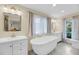 Bright bathroom featuring double vanities, a soaking tub, and tiled floors at 1009 Seacrest Ln, Folly Beach, SC 29439