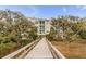 Exterior view of building with dock access and lush landscape with mature trees at 108 Fairbanks Oak Aly # 302, Daniel Island, SC 29492