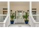 Elegant front entrance with glass-paneled door, stylish sconces, and potted plants, enhancing curb appeal at 124 Beresford Creek St, Charleston, SC 29492