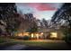 Charming single-story home with a well-manicured lawn, mature trees, and inviting curb appeal at twilight at 1327 Bob White Dr, Charleston, SC 29412