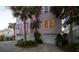Charming pink home exterior, featuring palm trees, a two-car garage, and landscaping at 19 Grand Pavilion Blvd, Isle of Palms, SC 29451