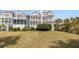 Beautiful two-story home with multiple balconies, a well-manicured lawn, and mature landscaping at 19 Grand Pavilion Blvd, Isle of Palms, SC 29451