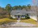 Charming green home with a covered front porch, surrounded by lush greenery and mature trees at 2101 Heavens Way, Summerville, SC 29483