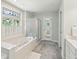 Bathroom featuring a soaking tub, glass enclosed shower, and gray tile floors at 601 Foredeck Ln, Edisto Island, SC 29438