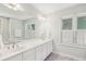 Bright bathroom featuring a double vanity with white cabinetry, a large mirror and natural light at 601 Foredeck Ln, Edisto Island, SC 29438