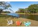 Cozy backyard featuring colorful Adirondack chairs, a tranquil waterfront, and mature trees at 728 N Godfrey Park Pl, Charleston, SC 29407