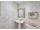 Charming powder room featuring wallpaper, pedestal sink, and decorative mirror at 728 N Godfrey Park Pl, Charleston, SC 29407