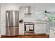 Bright kitchen with stainless steel refrigerator, stylish range hood, and subway tile backsplash at 728 N Godfrey Park Pl, Charleston, SC 29407