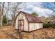 A white shed with red trim and a weathered roof sits in a leaf-covered backyard at 8 Shrewsbury Rd, Charleston, SC 29407