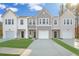 Charming townhomes featuring attached garages, concrete driveway, and manicured lawns against a blue, partly cloudy sky at 8745 Silver Perch Ln, North Charleston, SC 29420