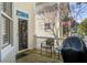 Cozy back porch with wooden floors, wicker chair and a grill under a blooming tree at 102 Barnaby St, Charleston, SC 29492