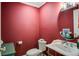 Powder room with bold red walls, pedestal sink, and oval mirror adding sophistication to the home's design at 102 Barnaby St, Charleston, SC 29492