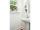 Bathroom features a white pedestal sink, round mirror, window and wood flooring at 1630 Balsam St, Charleston, SC 29407