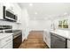 Well-lit kitchen with stainless appliances, white cabinets, and a view into the living area at 1630 Balsam St, Charleston, SC 29407
