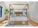Sunlit bedroom with a gold four-poster bed, light wood floors, and view of backyard at 299 Bampfield Dr, Mount Pleasant, SC 29464