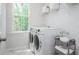 Efficient laundry room with modern washer and dryer, storage shelves, and a bright window, ideal for chores at 318 Archar St, Summerville, SC 29486