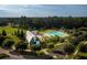 Aerial view of pool with umbrellas and barn with green siding in a wooded community on a sunny day at 318 Archar St, Summerville, SC 29486