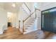 An elegant foyer features hardwood floors, stairs with a carpet runner, and a modern light fixture enhancing the home's entry at 3274 Heathland Way, Mount Pleasant, SC 29466